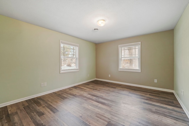 spare room featuring baseboards, a healthy amount of sunlight, and hardwood / wood-style flooring