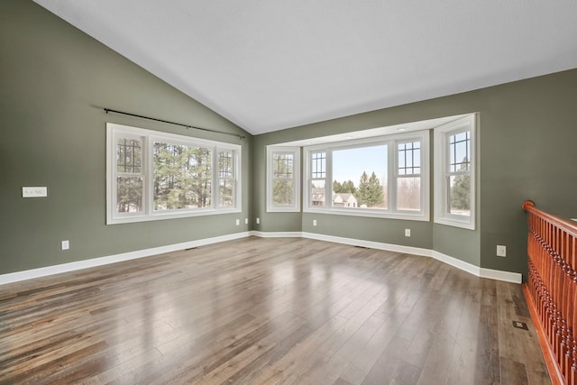 empty room with baseboards, lofted ceiling, and wood finished floors