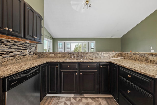 kitchen with dishwasher, a sink, lofted ceiling, and light stone counters