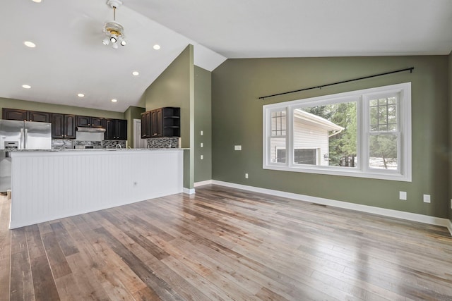 unfurnished living room featuring baseboards, light wood-style flooring, vaulted ceiling, and recessed lighting