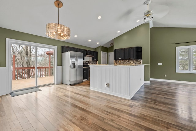 kitchen featuring stainless steel fridge, a peninsula, hanging light fixtures, under cabinet range hood, and light wood-style floors