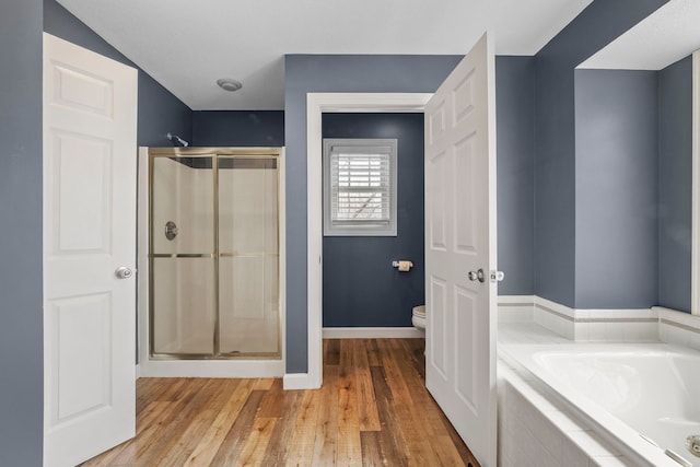 full bathroom with a bath, toilet, baseboards, a shower stall, and wood finished floors