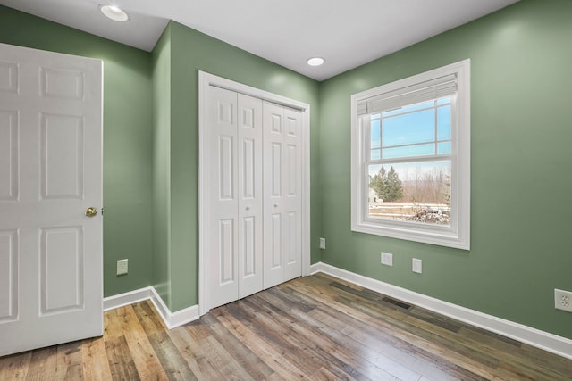 unfurnished bedroom with baseboards, a closet, and wood finished floors