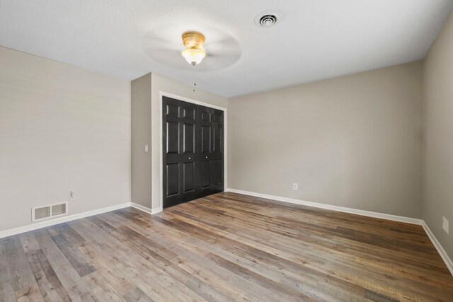 interior space featuring wood finished floors, baseboards, ceiling fan, and visible vents