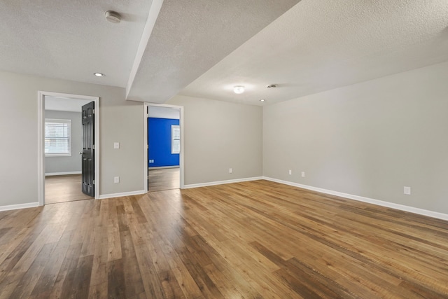 empty room featuring hardwood / wood-style floors, baseboards, and a textured ceiling