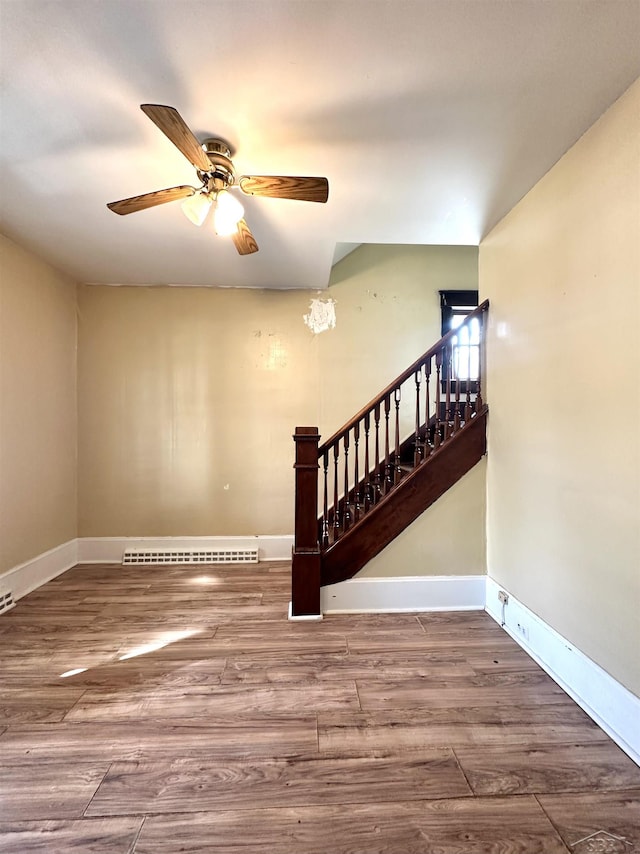 639 N Center St, Sebewaing, MI 48759 - unfurnished living room featuring a ceiling fan, wood finished floors, stairs, and baseboard heating