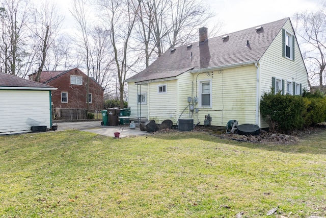 rear view of property with a patio, a lawn, roof with shingles, and a chimney