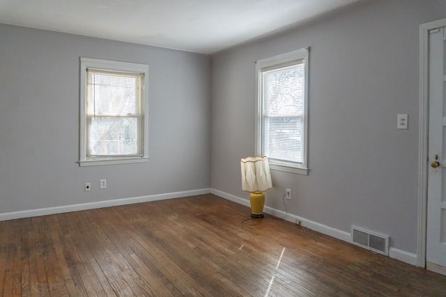 spare room with hardwood / wood-style floors, baseboards, and visible vents