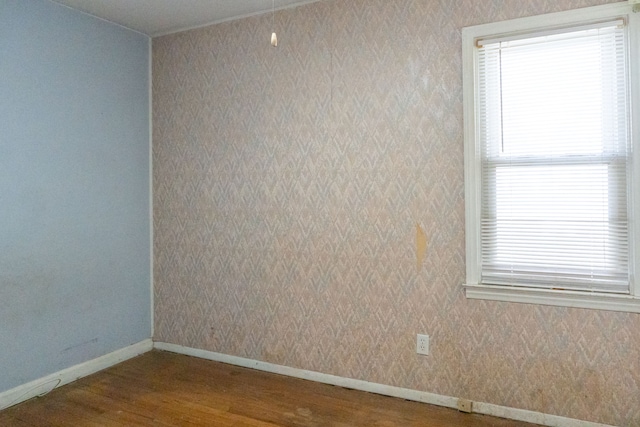 spare room featuring wallpapered walls and wood finished floors