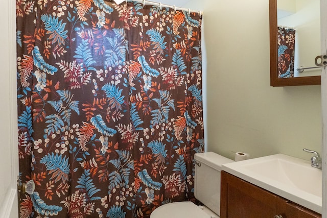 bathroom featuring toilet, vanity, and a shower with curtain