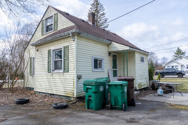 exterior space with a chimney and roof with shingles