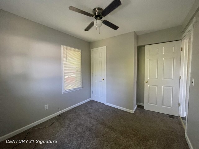 unfurnished bedroom with baseboards, dark carpet, and a ceiling fan