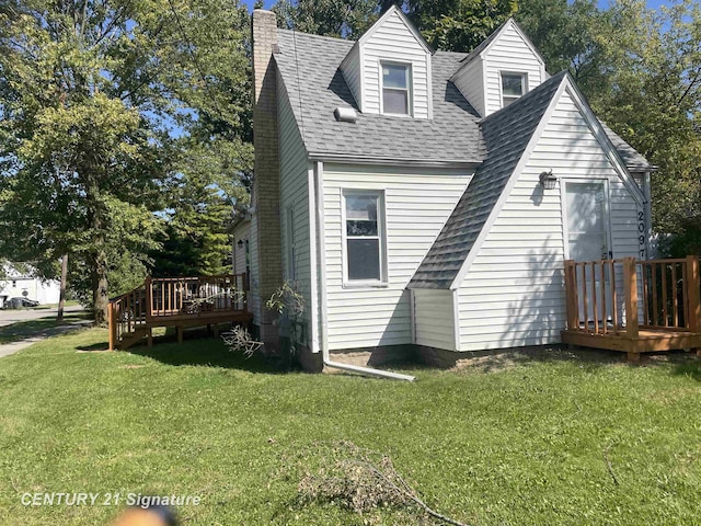 rear view of property with a yard, a deck, roof with shingles, and a chimney