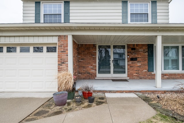 entrance to property featuring brick siding, a porch, and a garage