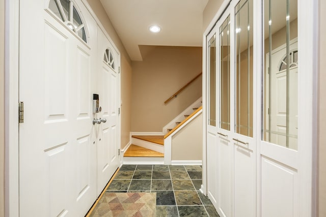 doorway to outside featuring baseboards, recessed lighting, stone finish floor, and stairway