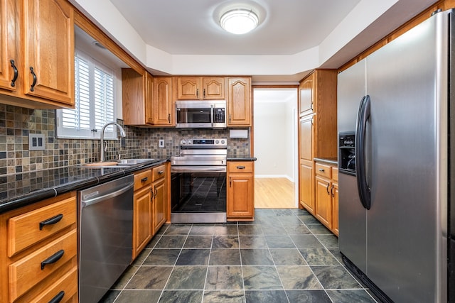 kitchen with brown cabinets, decorative backsplash, a sink, and stainless steel appliances