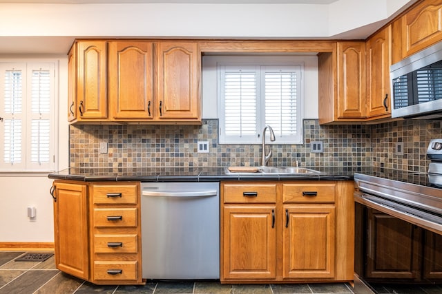 kitchen with a sink, stainless steel appliances, backsplash, and brown cabinets