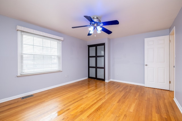 empty room with baseboards, light wood-style flooring, visible vents, and a ceiling fan