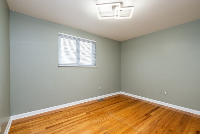 unfurnished room featuring baseboards, light wood finished floors, and visible vents