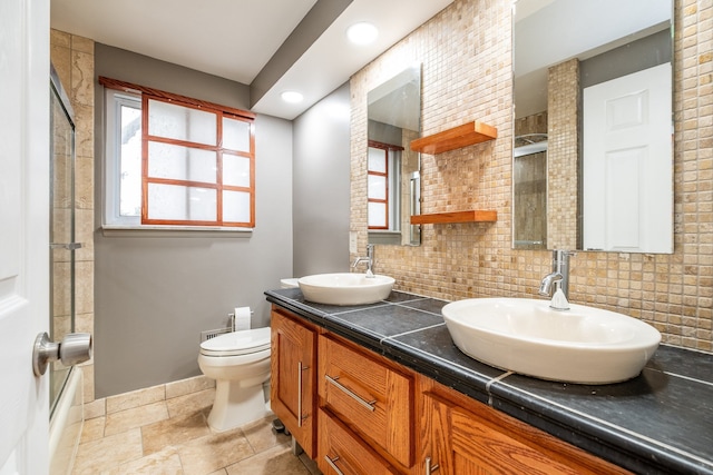 bathroom featuring decorative backsplash, double vanity, a sink, and toilet