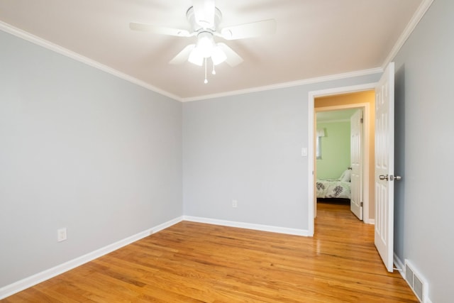 unfurnished room featuring baseboards, light wood-style flooring, visible vents, and crown molding