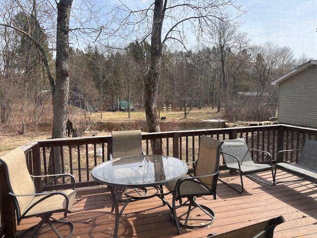 8034 N Johnson Rd, Irons, MI 49644 - wooden terrace with outdoor dining area and a view of trees