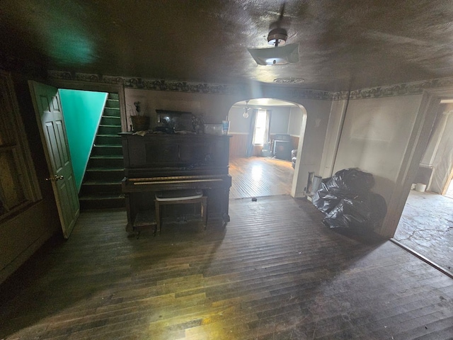interior space with stairs, wainscoting, arched walkways, and wood-type flooring