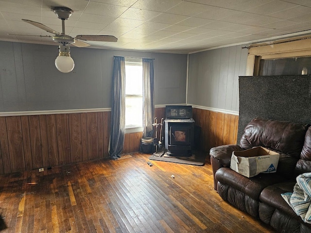 living room featuring a wood stove, a ceiling fan, and wood-type flooring