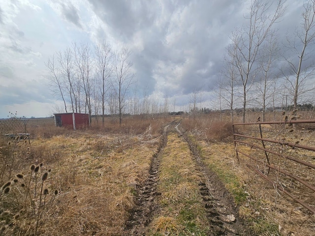 view of yard featuring an outdoor structure, fence, and a rural view