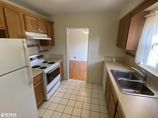 6007 Corunna Rd, Flint, MI 48532 - kitchen featuring white appliances, under cabinet range hood, a sink, brown cabinets, and light tile patterned floors