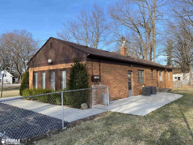 6007 Corunna Rd, Flint, MI 48532 - view of side of property with a chimney, a patio, central AC unit, brick siding, and a gate