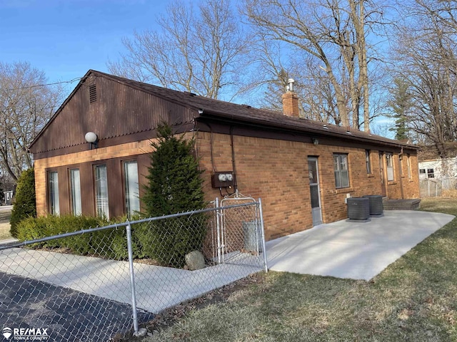 6007 Corunna Rd, Flint, MI 48532 - view of side of home featuring a chimney, a patio, brick siding, and central AC unit
