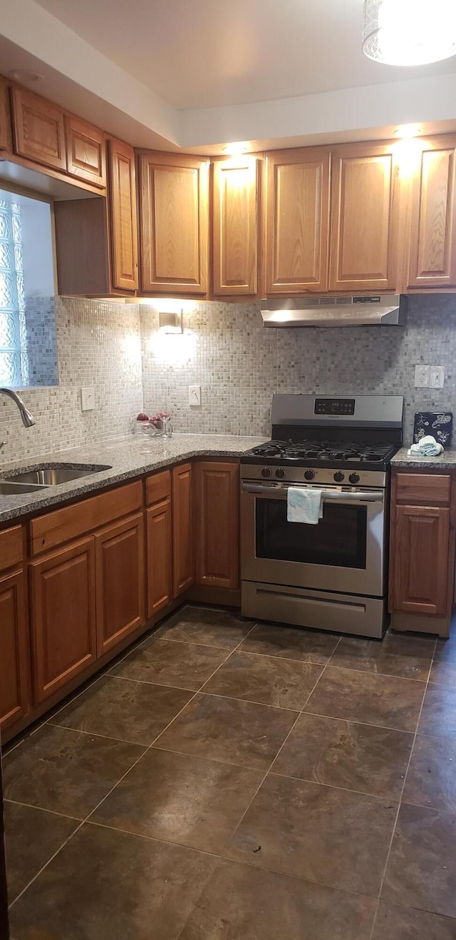 1139 Atkinson St, Detroit, MI 48202 - kitchen with stainless steel gas stove, under cabinet range hood, a sink, backsplash, and stone countertops