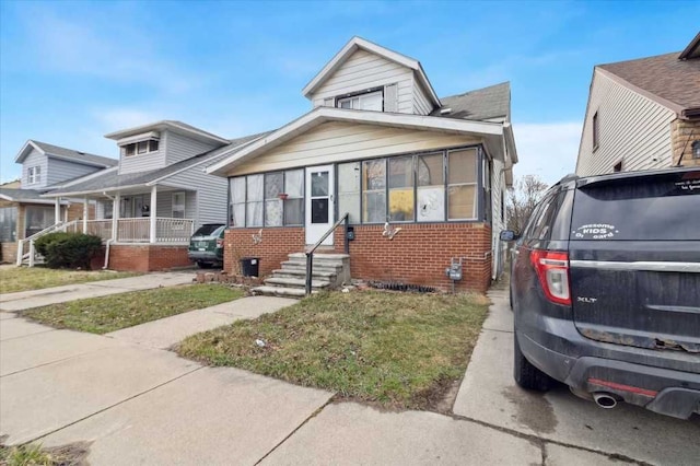 bungalow-style house with entry steps, a porch, and brick siding