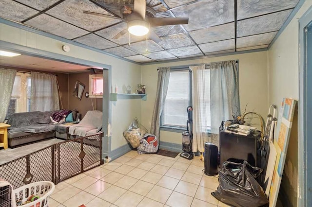 living area featuring tile patterned floors, ceiling fan, and baseboards