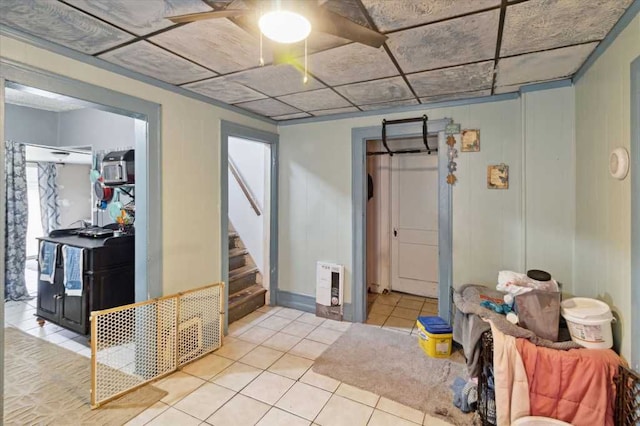 below grade area with heating unit, tile patterned floors, stairway, and a ceiling fan