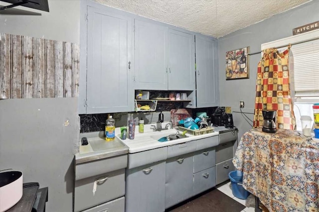 kitchen with gray cabinets, light countertops, a sink, and a textured ceiling