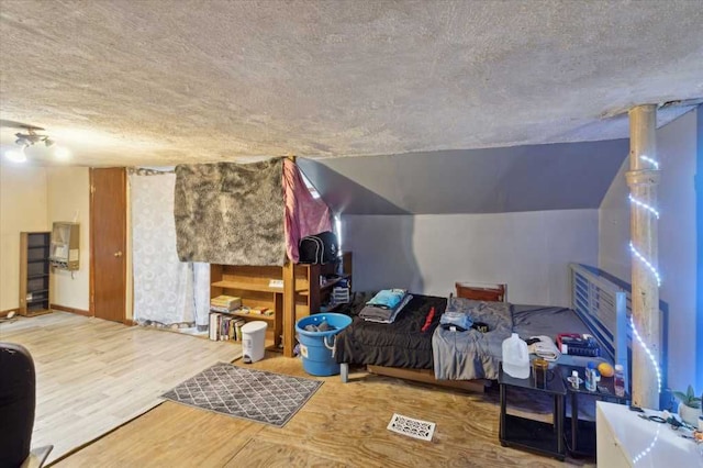 bonus room with a textured ceiling, wood finished floors, and vaulted ceiling