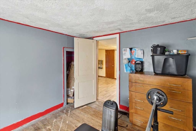 interior space with baseboards, a textured ceiling, and wood finished floors