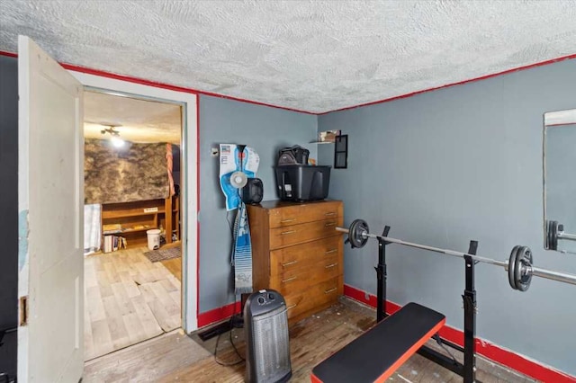 exercise room featuring a textured ceiling and wood finished floors