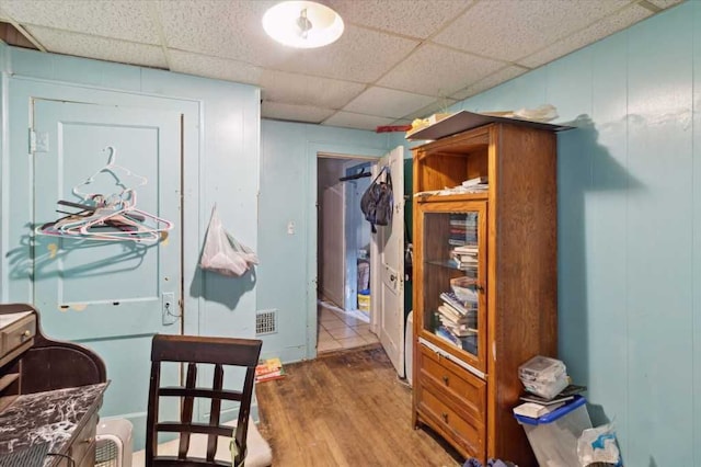 corridor featuring visible vents, wood finished floors, and a drop ceiling