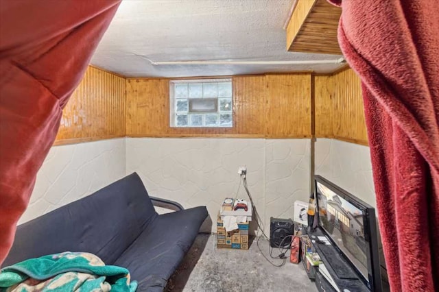 living area with concrete block wall, concrete floors, wood walls, and a textured ceiling
