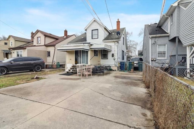 view of front of property with a chimney and fence
