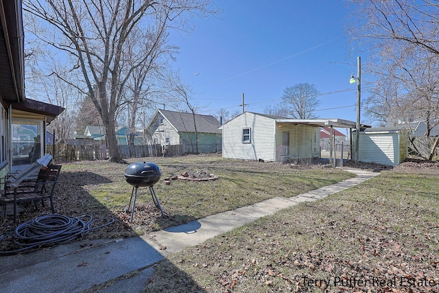view of yard with fence, an outbuilding, and a carport