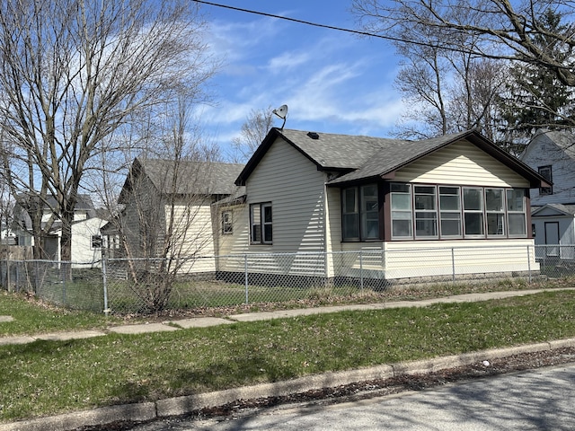 view of side of property with a lawn, a shingled roof, a sunroom, and fence private yard