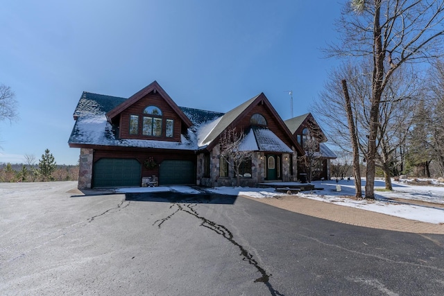chalet / cabin featuring stone siding, aphalt driveway, and a garage
