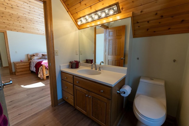 ensuite bathroom with vanity, vaulted ceiling, toilet, ensuite bath, and wood finished floors