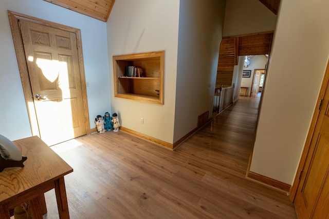 hall with baseboards, high vaulted ceiling, wood finished floors, and wood ceiling