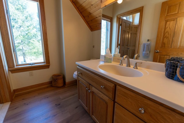 bathroom with baseboards, wood finished floors, toilet, vanity, and lofted ceiling