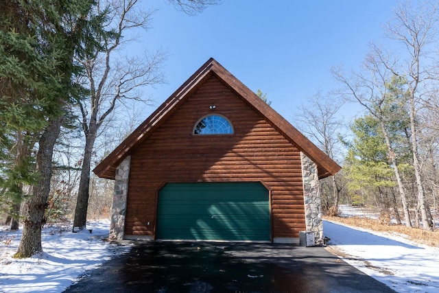 snow covered garage featuring aphalt driveway